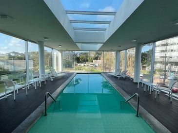 Indoor swimming pool with glass walls and skylight.