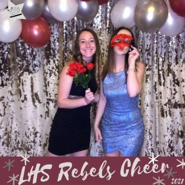 Two young women posing with balloons at a cheer event.