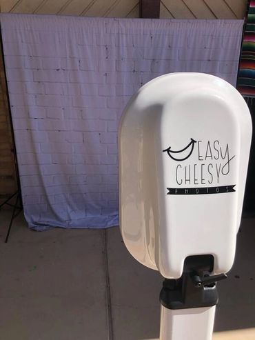 Photo booth labeled 'Easy Cheesy' with a cloth backdrop.