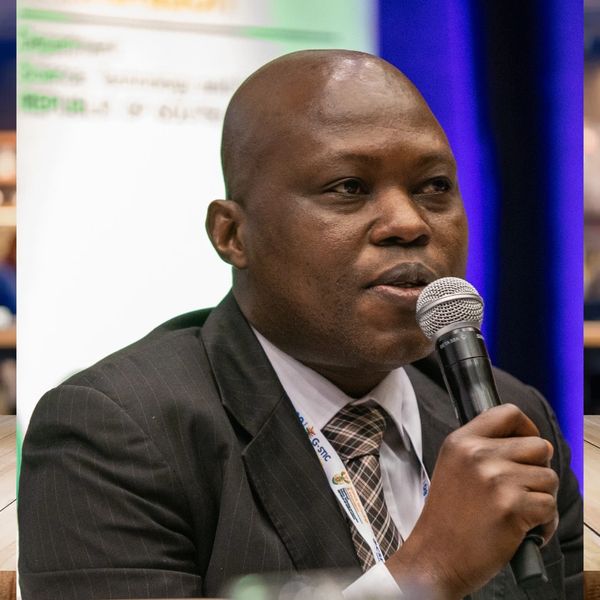 Man in suit speaking into a microphone at an event.