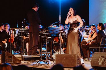 Female singer performing with an orchestra on stage.