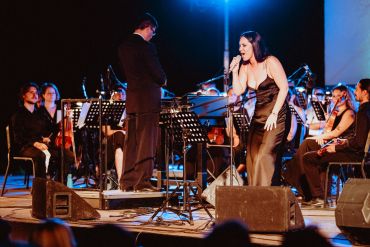 Female singer performing with orchestra on stage.