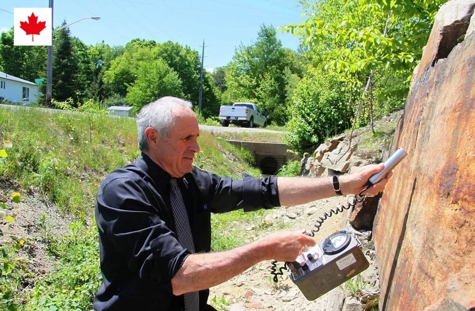 Man conducting a geological survey with equipment on a rock face.