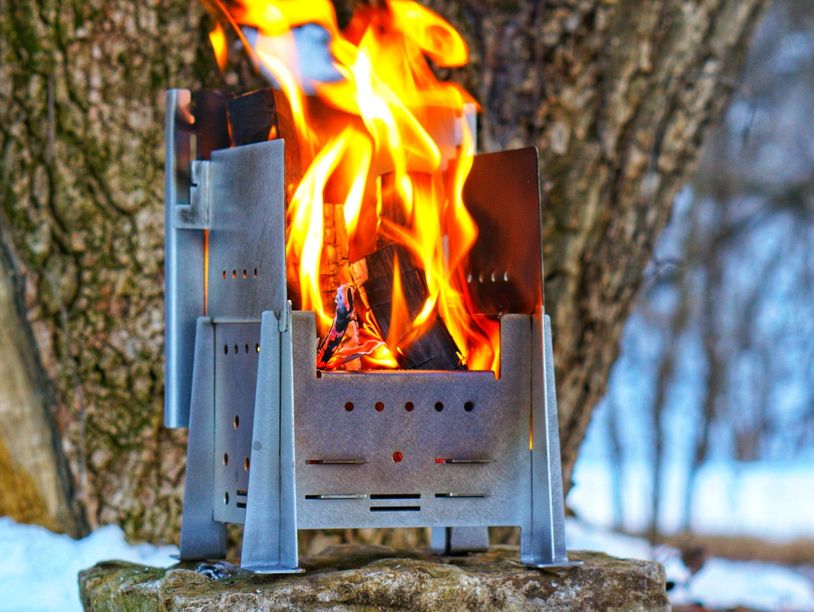 Compact metal fire pit with bright flames outdoors in winter.