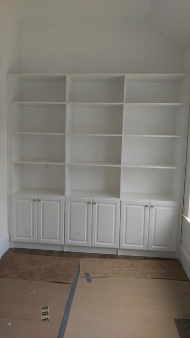 White built-in shelves with cabinets in an empty room.