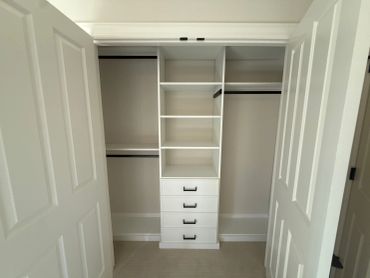 Empty white closet with shelves and drawers.
