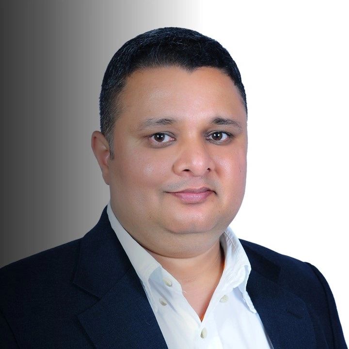 Professional headshot of a man in a suit with a neutral background.