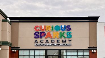 Colorful Curious Sparks Academy sign on a building facade.