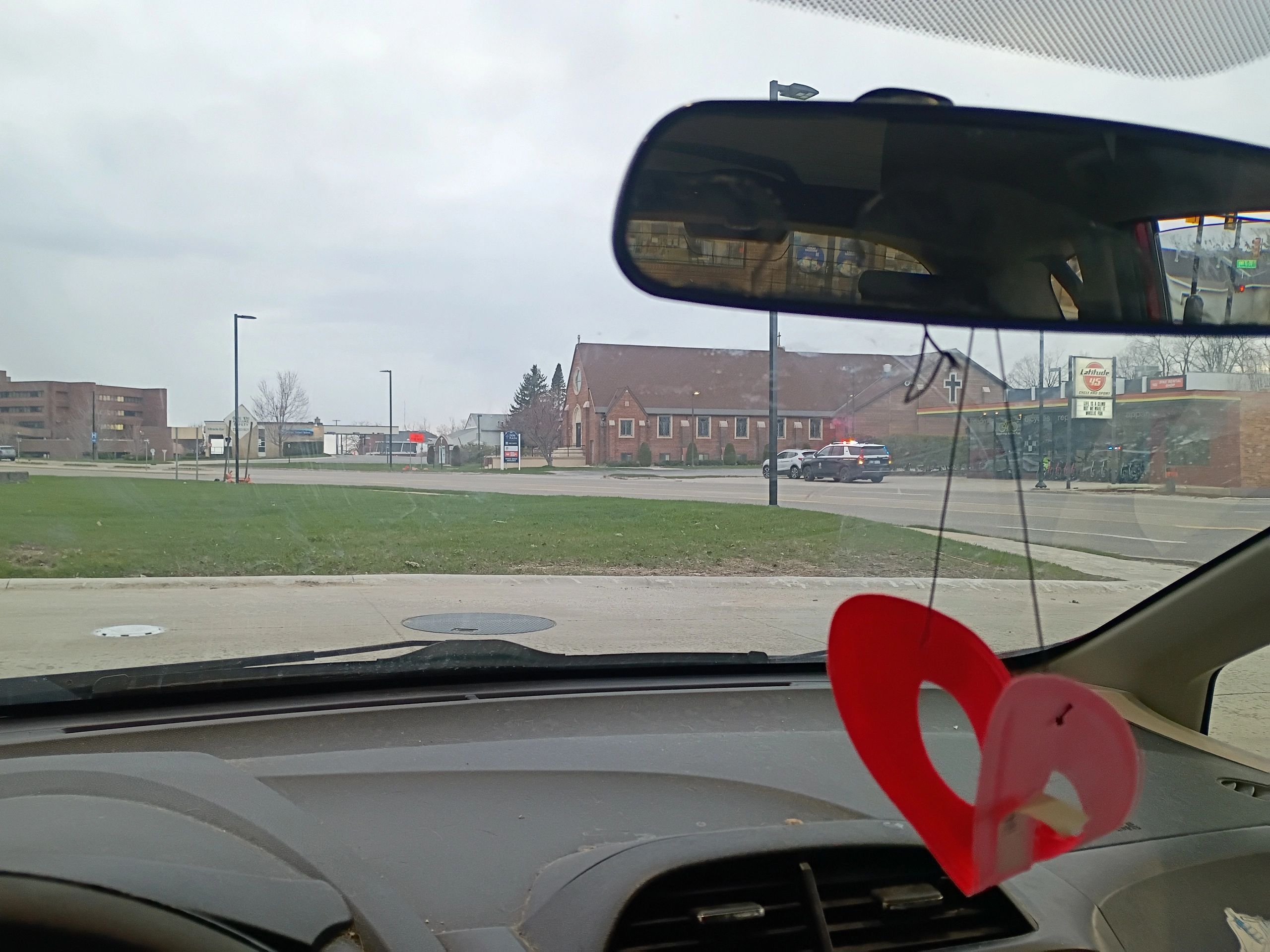 View from inside a car showing a street, a church, and a police car with flashing lights.