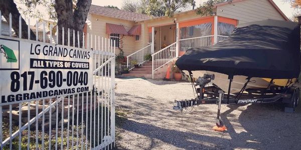 House with a boat covered in black tarp and a sign for LG Grand Canvas.