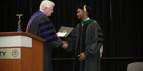 Photo of Doctor Bonzo accepting Teacher of the Year award at Mercer's medical school graduation