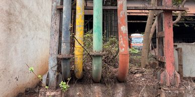 Four colorful pipes running down a wall.