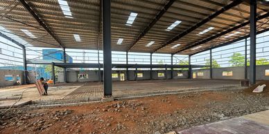 A large industrial building under construction with a worker inside.
