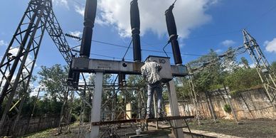 A worker repairing power equipment outdoors.