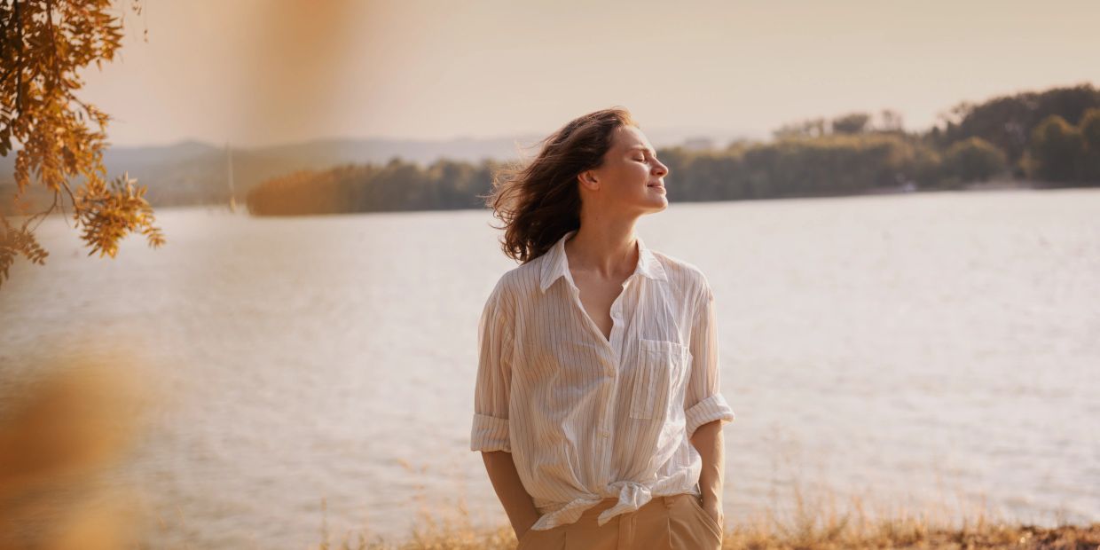Woman enjoying a peaceful moment by the lake at sunset.
