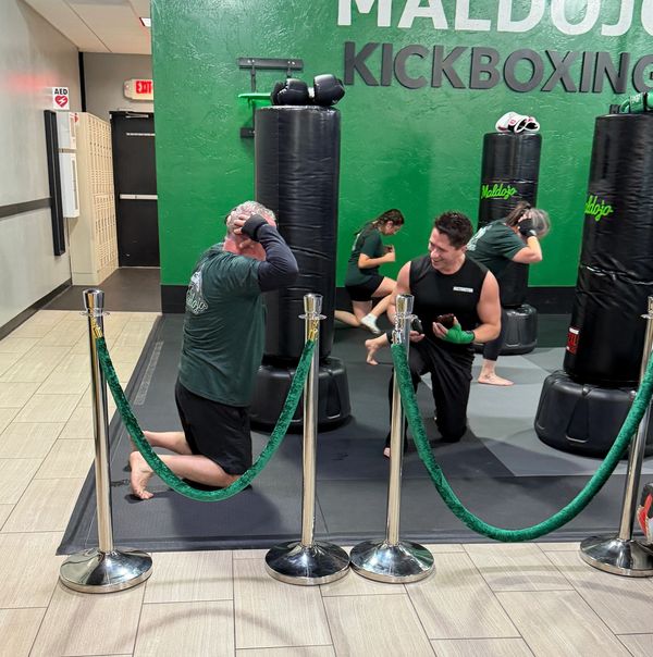 People training kickboxing indoors with punching bags and gloves.