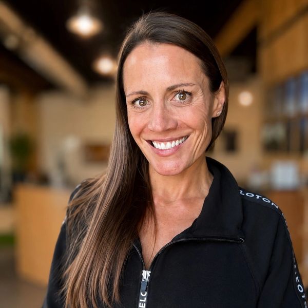 Smiling woman with long brown hair in a black jacket.