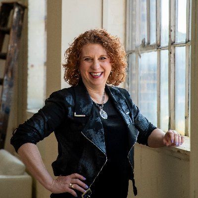 Smiling woman with curly hair by a window.