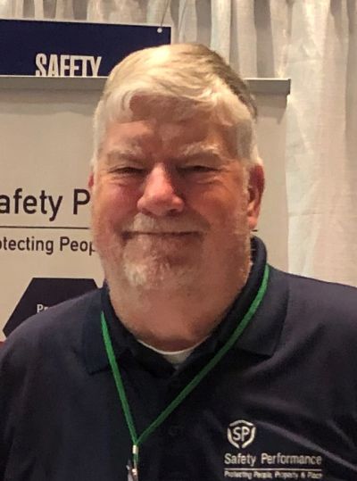 Older man smiling in a navy shirt with Safety Performance logo.