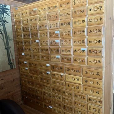 Traditional wooden apothecary cabinet with numerous labeled drawers.