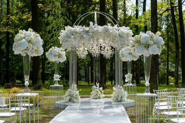 White floral arch, white stage with glass vase, wedding planner designer decor