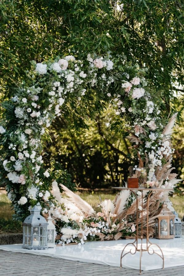 Outside floral arch, white stage with glass vase, wedding planner designer decor, lanterns 