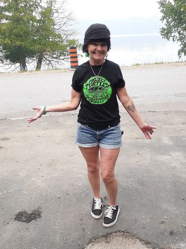 A smiling woman in a Teenage Mutant Ninja Turtles t-shirt and shorts outdoors.