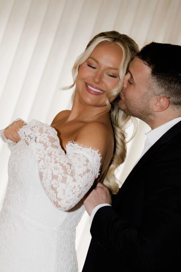 Newlyweds share a tender moment with a loving kiss on the bride's cheek.