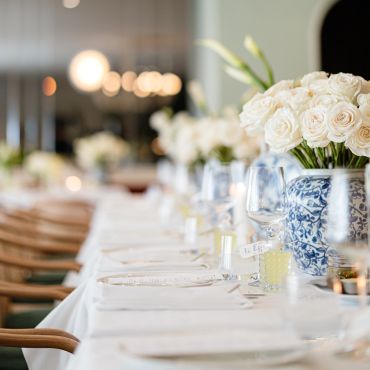 Elegant dining table set with white roses and glassware for a formal event.