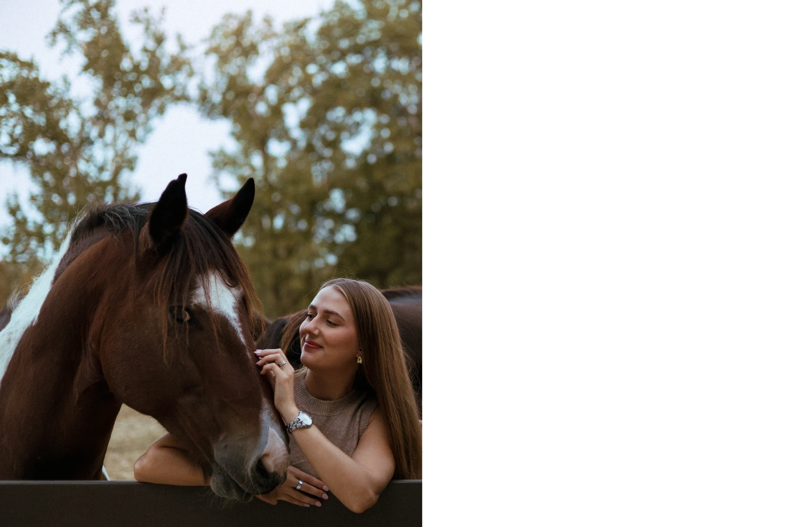 A woman affectionately pets a brown and white horse outdoors.