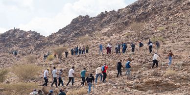 Group of people hiking up a rocky hill in a line.