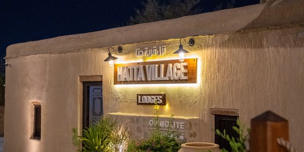 Hatta Village Lodges illuminated at night with plants in front.