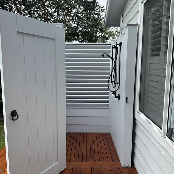 Custom outdoor shower built on hardwood deck with running drain and custom door.