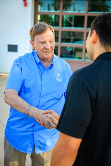 Two men shaking hands outdoors.