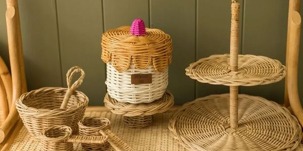 Wicker basket set with a honey jar and tiered tray on a woven surface.
