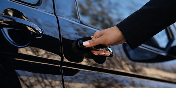 Hand opening a black car door with well-manicured nails.