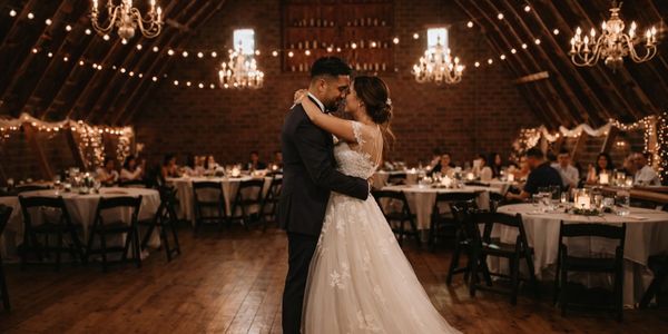 Newlyweds sharing a tender first dance in a warmly lit rustic venue.