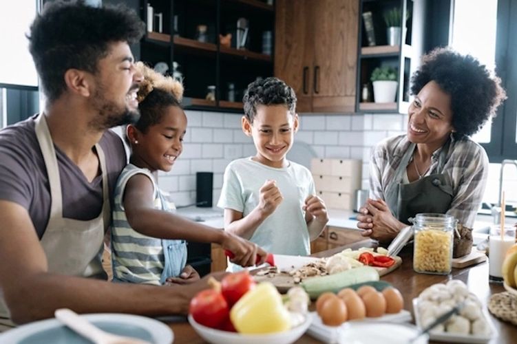 Happy family around kitchen table, preparing foods, the young son and daughter getting involved too.