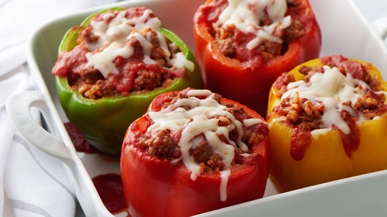 Image of a tray of roasted stuffed green, red and yellow peppers, topped with melted cheese garnish.