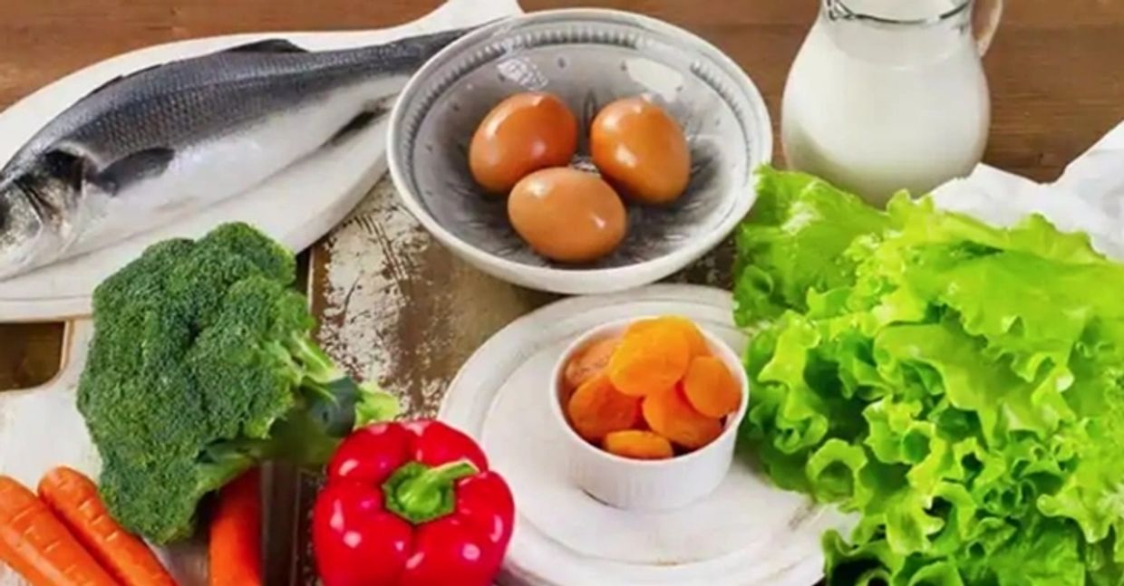 Large assortment of foods, each of which possesses Vitamin A in some way or other, on kitchen table.