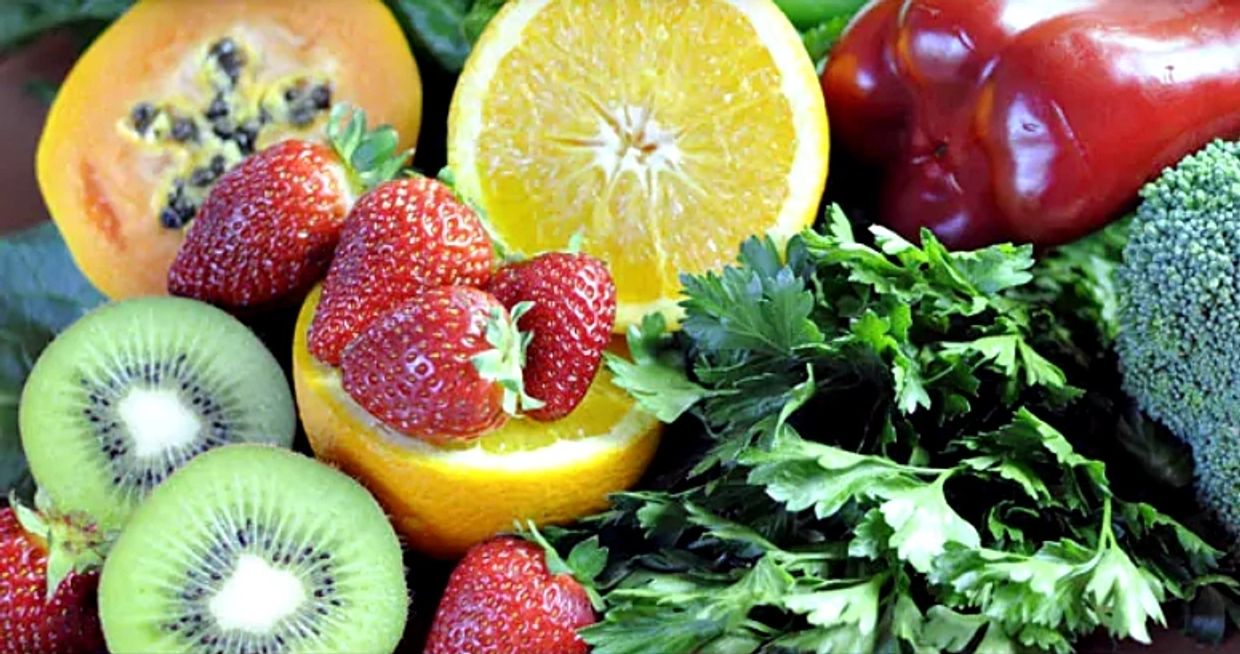 Group of fruits and vegetables with Vitamin C content, including citrus fruit, kiwis, kale, broccoli