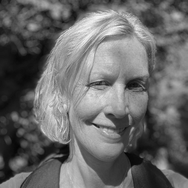 Smiling woman with blonde hair outdoors in natural light.