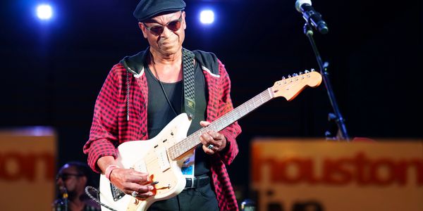 Musician playing electric guitar on stage.