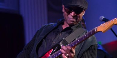 A musician passionately playing an electric guitar on stage.