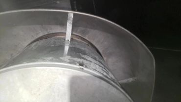 Close-up of a metallic vent or duct with a curved shield.