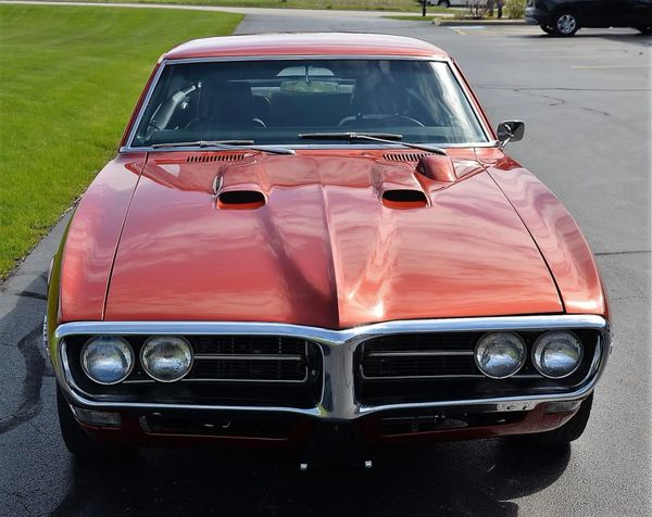 Front view of a classic red muscle car with dual hood scoops.