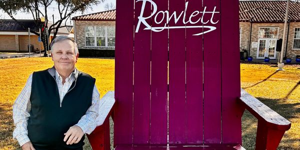 Carter Holston at the big burgundy chair in the Village of Rowlett Downtown