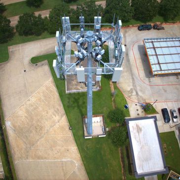 Aerial view of a large cell tower surrounded by parking lots and buildings.