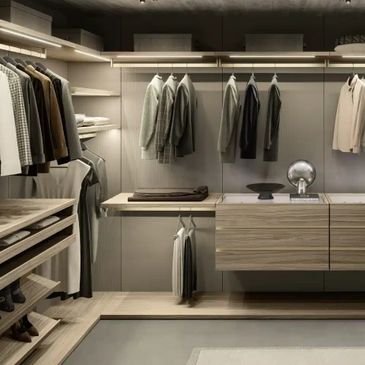 Modern walk-in closet with neutral-toned clothes and wooden shelves.