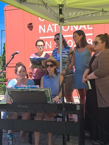 Group of women performing music outdoors.